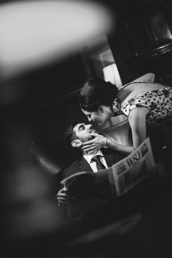 Mad Men inspired engagement shoot with bride and groom kissing in historic bar venue