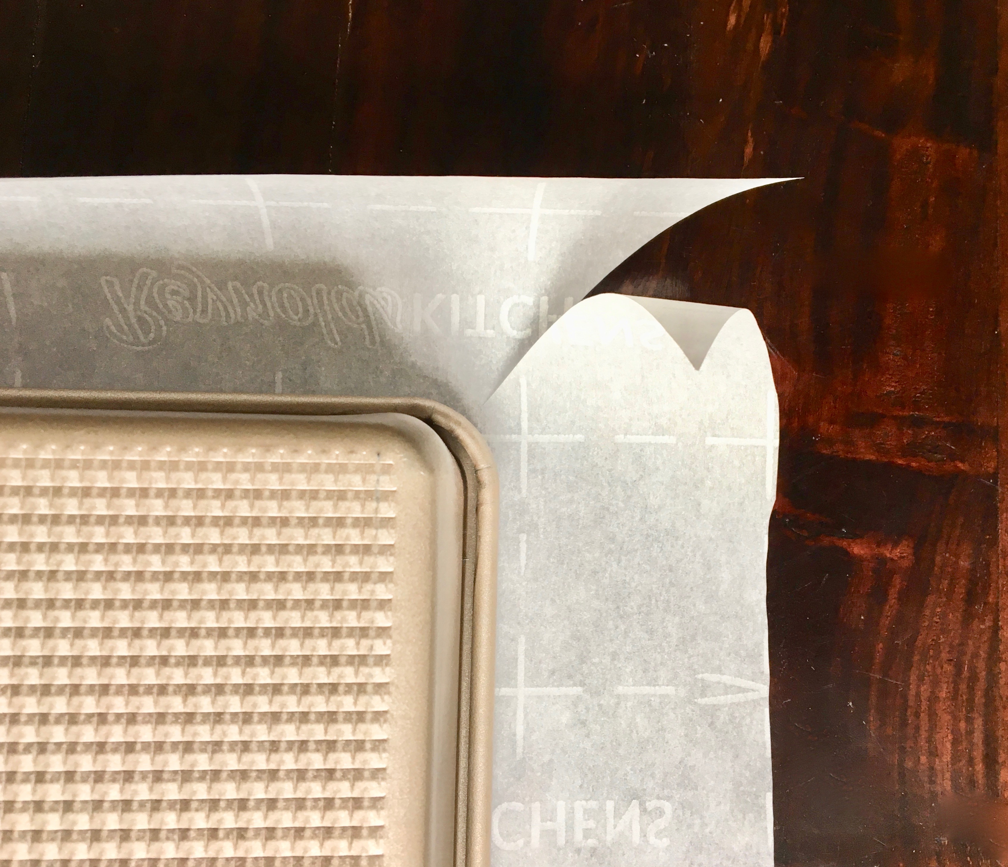 Display of how to cut the corner of parchment paper to fit your baking tin for baking.