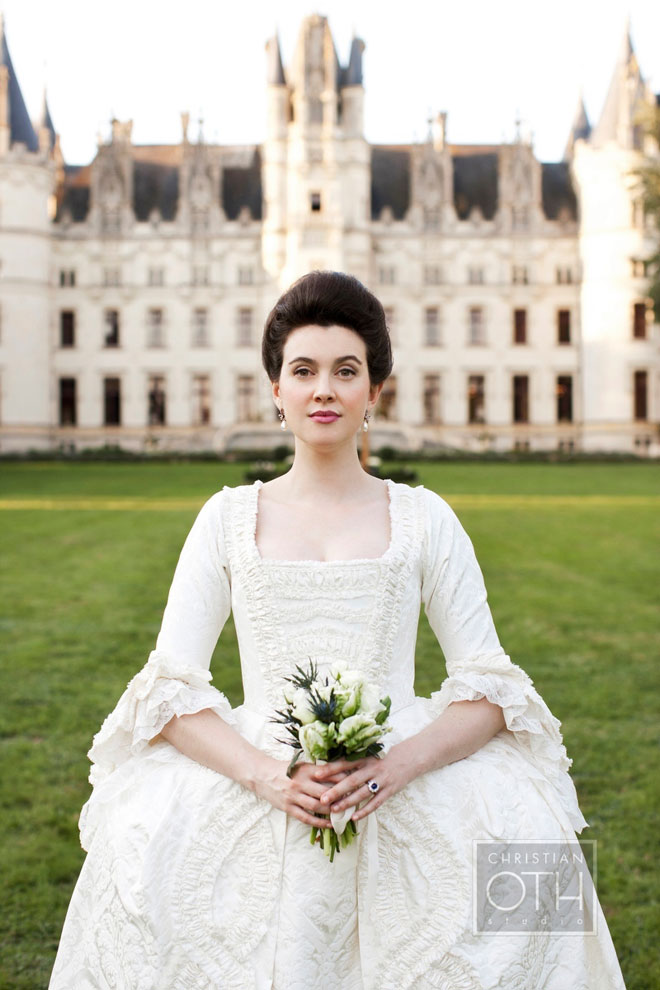 Marie Antoinette inspired wedding - bride dressed in historically accurate wedding gown with bouquet in front of palace venue