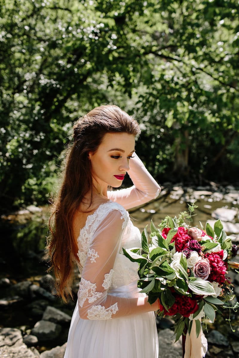 vintage forest styled shoot bride looking at bouquet