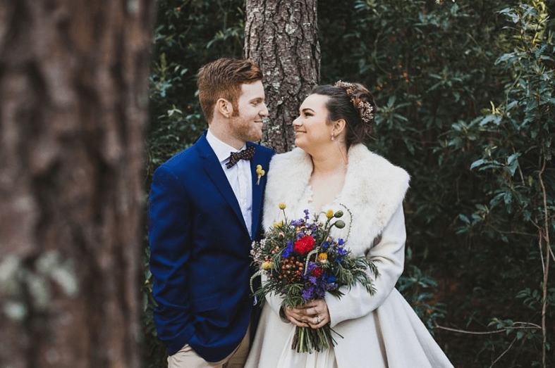 bride and groom in forest with wildflower bouquet