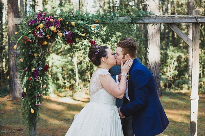 bride and groom kissing at wildflower altar